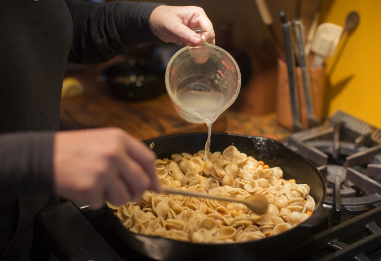 Christine Burns Rudalevige pours a bit of the pasta water into her Double Garlic Chickpea Pasta.