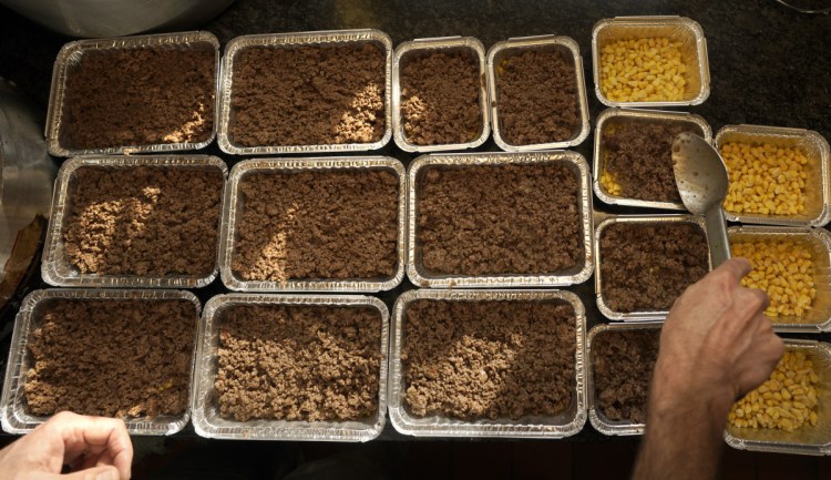 Peter Leavitt spoons ground beef into a take-out container of shepherd's pie at Leavitt & Sons Deli in Portland on Monday. Leavitt says sales of the comfort foods he sells – shepherd's pie, chicken potpie and mac-and-cheese – have noticeably risen.