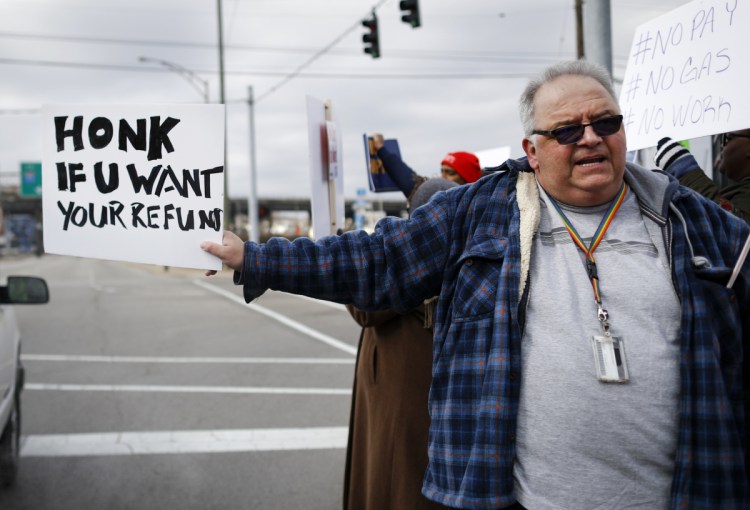 Will Kohler, an IRS tax examiner, joins federal employees calling for an end to the partial government shutdown outside the IRS office in Covington, Ky.