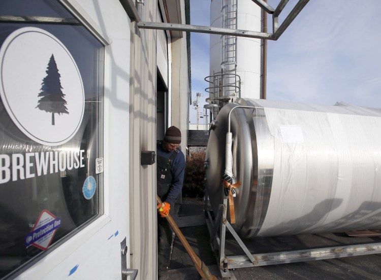 Cote Crane & Rigging foreman Brian Bosse prepares to guide a 2,500-gallon fermenting tank into Lone Pine Brewing Co.'s Gorham facility on Tuesday.