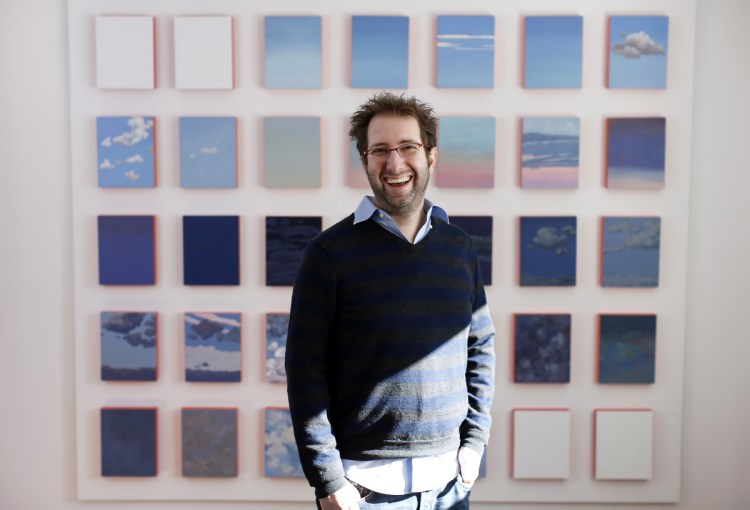 Sam Carner with paintings by his late mother, who taught art at the University of Southern Maine, at his boyhood home in Falmouth.