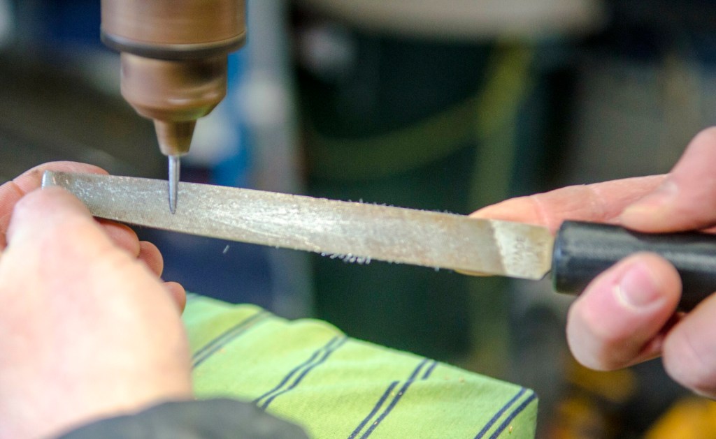 William Terry files down a galvanized roofing nail to be a cribbage board peg on Feb. 2 in Richmond. He makes the other, different-colored set from copper roofing nails.