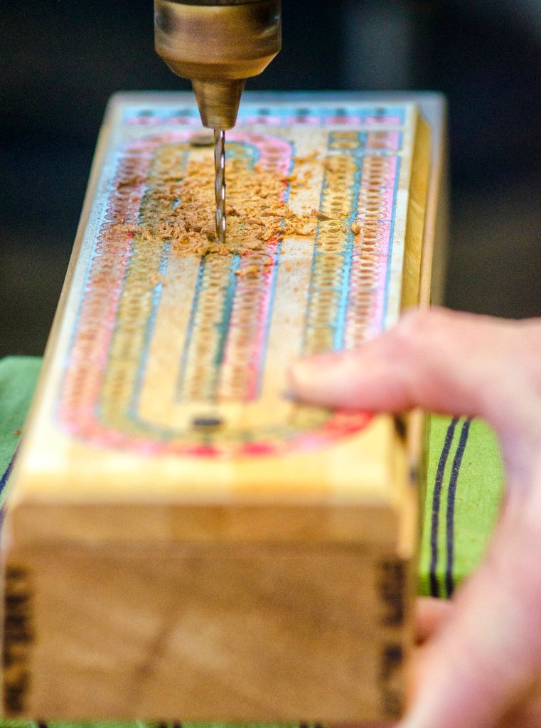 William Terry uses a drill press to drill holes into a cribbage board that he's making Feb. 2 in Richmond. He uses an old cribbage board as a guide.