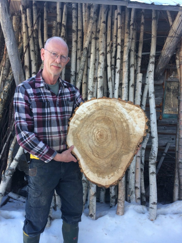 Lifelong Jackman resident Rene Guay holds a kiln-dried Balm of Gilead slice that will be used as the top of an end table. Guay's online wood product business, Spirt of the Woods, has been negatively impacted by Central Maine Power Co.'s unreliable service in the area, which leads to frequent internet outages and has caused delays to the kiln-drying process. Guay said he has lost thousands of dollars in revenue over the last several years as a result.