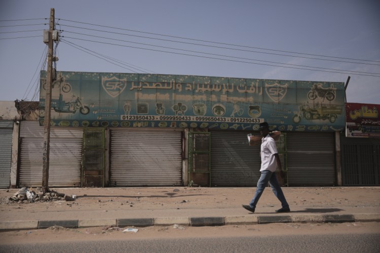 A man walks past  shops that remain shuttered after the military unseated the government this week in Khartoum, Sudan, on Thursday.