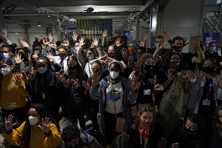 Youngsters, with eyes drawn on their hands to show they are watching and 1.5 for countries to keep warming below 1.5 degrees Celsius, take part in a Fridays for Future climate protest inside a plenary corridor at the SEC (Scottish Event Campus) venue for the COP26 U.N. Climate Summit, in Glasgow, Scotland, Wednesday, Nov. 10.