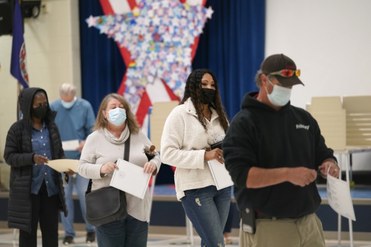 Voters hold their ballots as they wait in line to cast their votes at a school in Midlothian, Va., on Tuesday. 