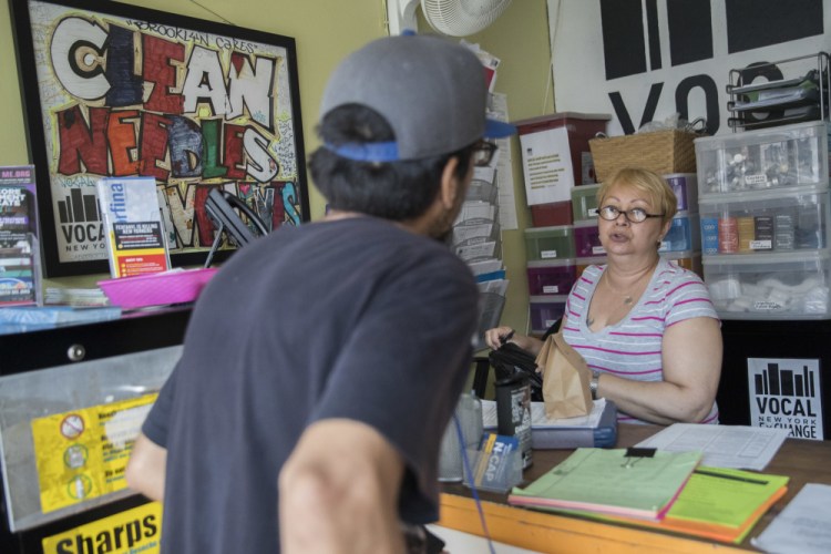 Evelyn Milan, right, director of services at VOCAL-NY, prepares a package with sterile injecting equipment for a member at the organization's headquarters in the Brooklyn borough of New York, in July 2018. The injection site will have monitors who watch for signs of overdose and can administer an antidote if needed. It can provide clean needs and referrals to treatment centers.