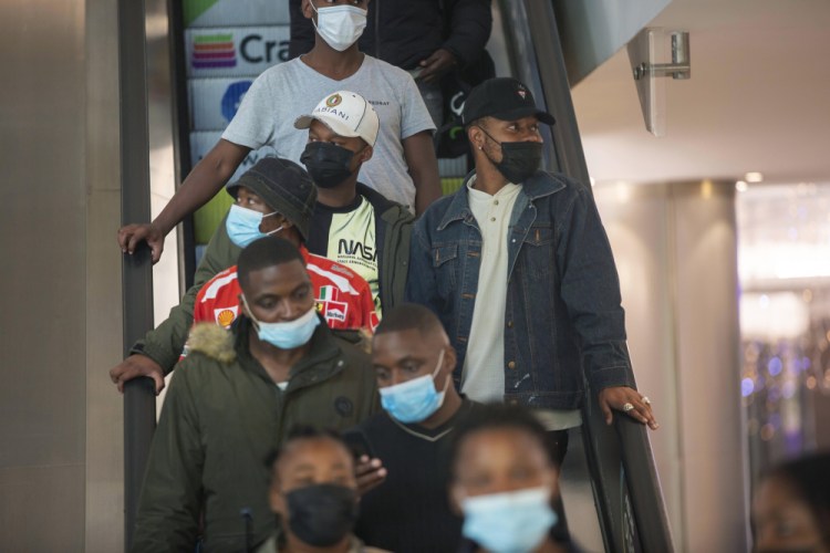 People wearing masks on an escalator at a shopping mall, in Johannesburg, South Africa, Friday Nov. 26, 2021. 