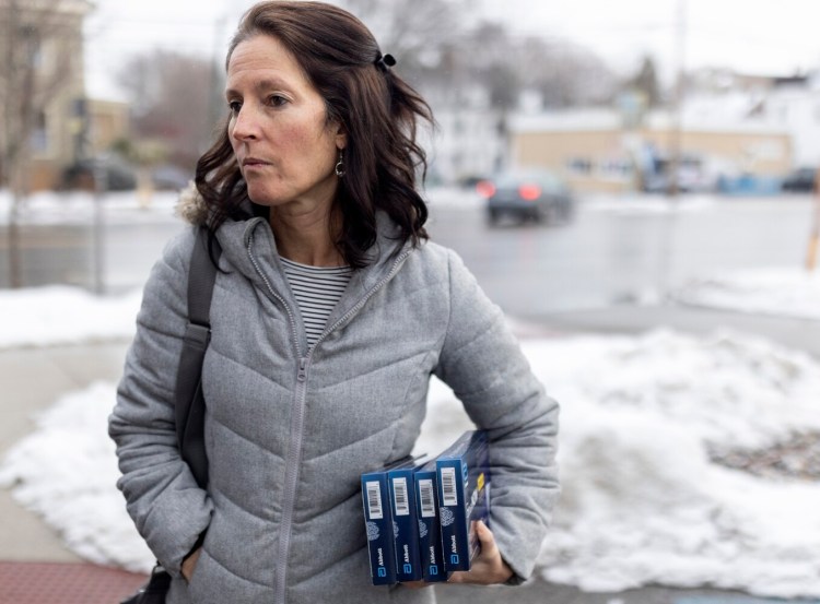 Ann-Marie Bouchard holds at-home COVID-19 tests that she bought at Walgreens on Forest Avenue on Thursday. She and her husband bought six tests total, some to give away and others for their family to use before upcoming travel or in case of exposure.