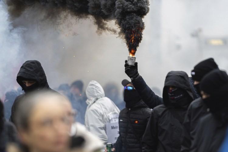 Protesters light flares during a rally against measures to battle the pandemic, in Vienna, Austria this month.

