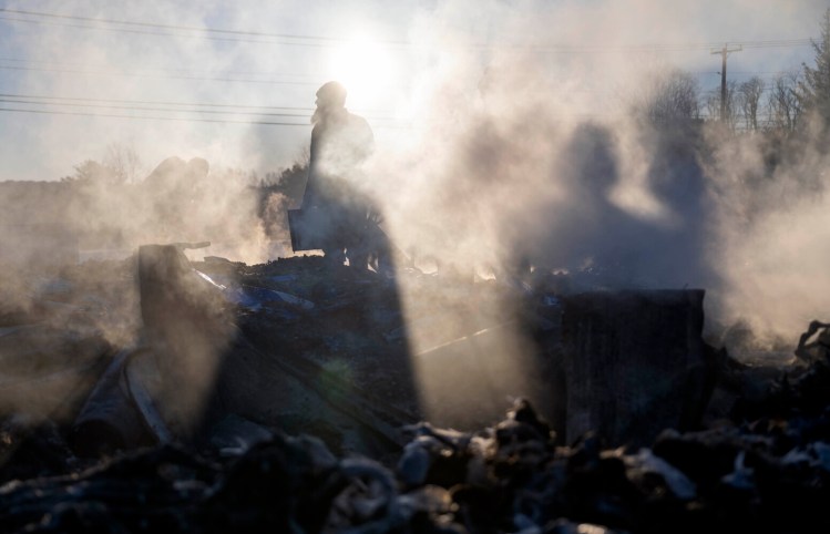 Members of the Amish community in Unity clear away debris Friday from the charred remains of the Unity Community Market a day after a fire destroyed the building.