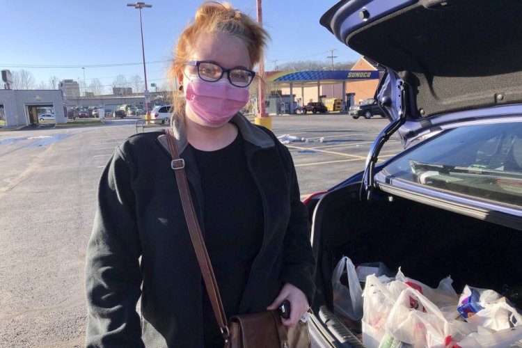 Hairdresser Chelsea Woody stands outside her car at a grocery store Tuesday in Charleston, W.Va. For the first time in half a year, families on Jan. 14 are going without a monthly deposit from the federal child tax credit. Woody, a single mother, relied on the check to help raise her young son. 