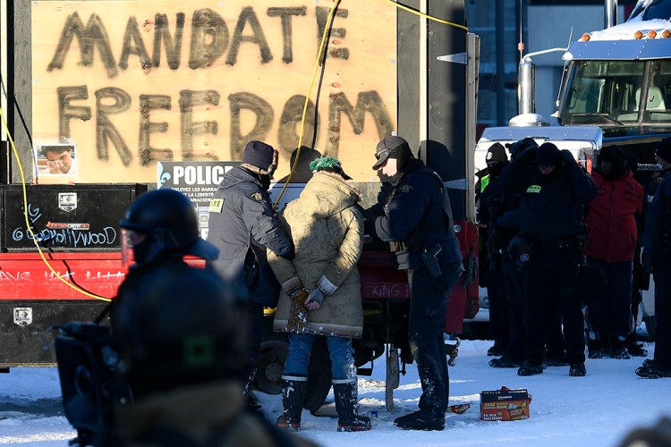 Police officers take a protester into custody Friday in Ottawa as they move to end a protest that started in opposition to COVID-19 vaccine mandates and grew into a broader anti-government demonstration and occupation.