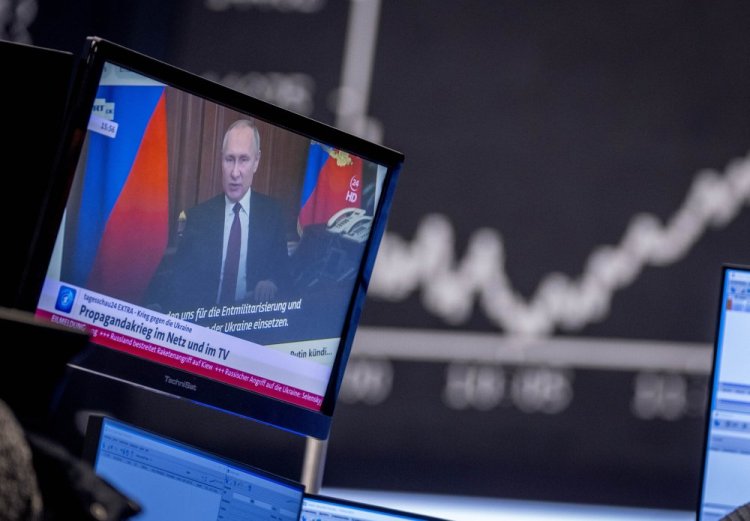 Russia's President Vladimir Putin appears on a television screen at the stock market in Frankfurt, Germany on Feb. 25.. Russia is revving up its sophisticated propaganda machine as its military advances in neighboring Ukraine. Analysts who monitor propaganda and disinformation say they've seen a sharp increase in online activity linked to the Russian state in recent weeks. 