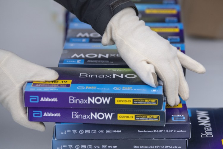 A Youngstown City Health Department worker grabs two at-home COVID-19 test kits to be handed out during a distribution event in Youngstown, Ohio.