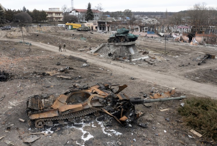 Local residents pass a damaged Russian tank in the town of Trostsyanets, some 250 miles east of Kyiv, Ukraine, on Monday. A senior U.S. defense official said Washington believes the Ukrainians have retaken the town.