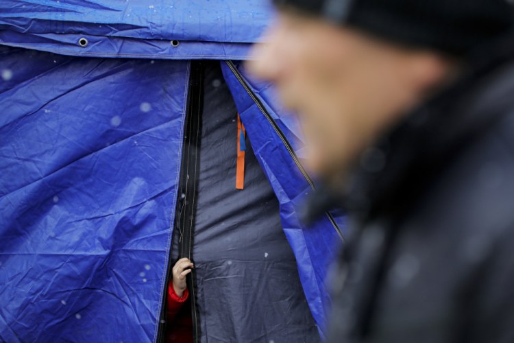 A refugee that fled the conflict from neighboring Ukraine sticks out her hand from a waiting area tent at the Romanian-Ukrainian border, in Siret, Romania, Thursday.