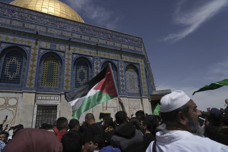 A worshipper waves the Palestinian flag after Friday prayers, hours after Israeli police clashed with protesters at the Al Aqsa Mosque compound in Jerusalem's Old City.