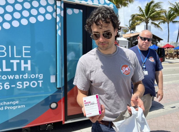 Huston Ochoa, a clinical counselor for The SPOT, hands out samples of Narcan, which can reduce opioid overdoses, to spring breakers on Fort Lauderdale Beach, Fla., on March 31. 