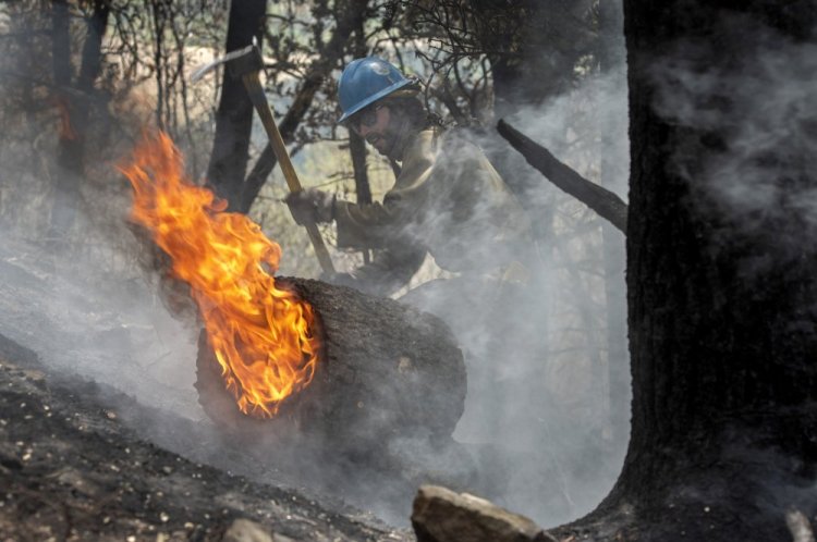 Carson Hot Shots Tyler Freeman keeps a burning log from rolling down a slope last month as he and his co-workers work on hot spots from the Calf Canyon/Hermits Peak Fire in the Carson National Forest west of Chacon, N.M. It is the largest fire to have burned this spring in the United States.