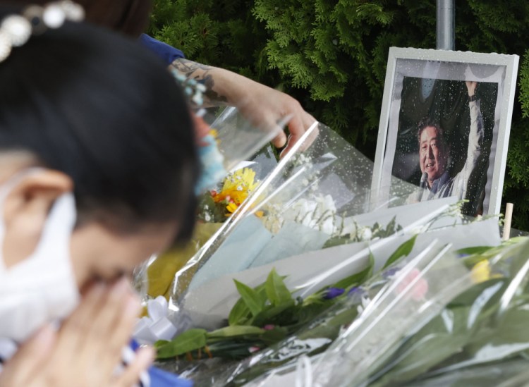 A photo of former Prime Minister Shinzo Abe is displayed on a makeshift memorial near the scene where Abe was fatally shot Friday while delivering a speech to support a Liberal Democratic Party's candidate in Nara.