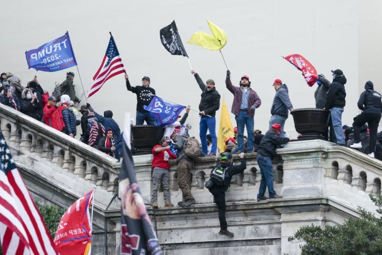 Rioters wave flags on the West Front of the U.S. Capitol in Washington on Jan. 6, 2021. As public trust in democratic institutions declines, conspiracy theories are filling the void. In some cases, that's leading believers to doubt even their own allies.