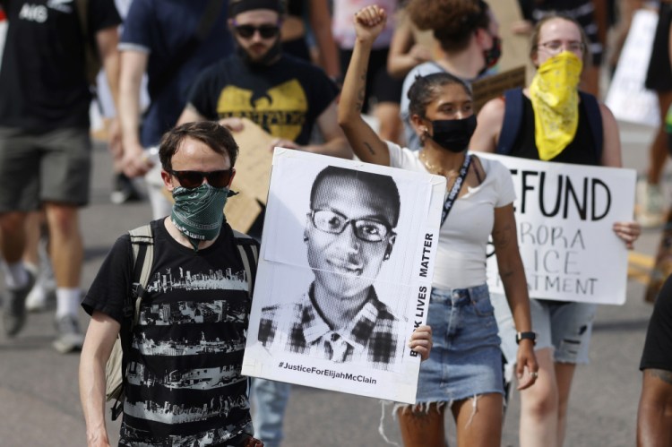 A demonstrator carries an image of Elijah McClain in Aurora, Colo., June 27, 2020. A Colorado judge on Friday released an amended autopsy report for McClain. 