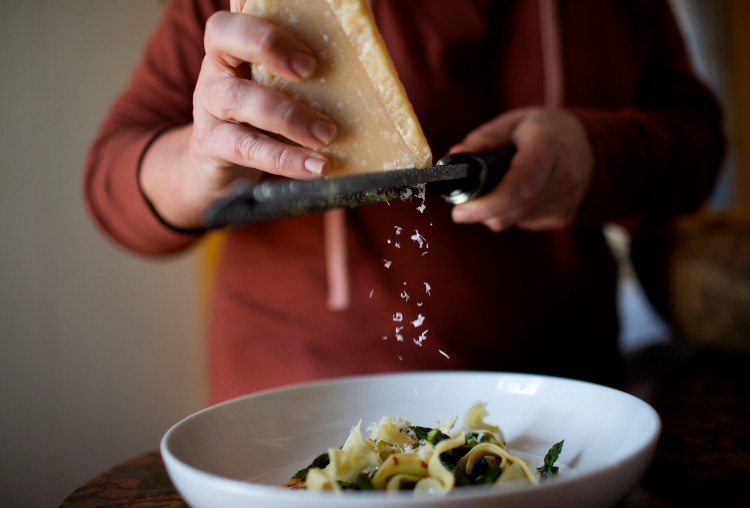 BRUNSWICK, ME - MARCH 30: Christine Burns Rudalevige grates parmesan cheese atop a finished plate of Goose egg asparagus pansoti with spicy brown butter and lemon. . (Staff photo by Derek Davis/Staff Photographer)